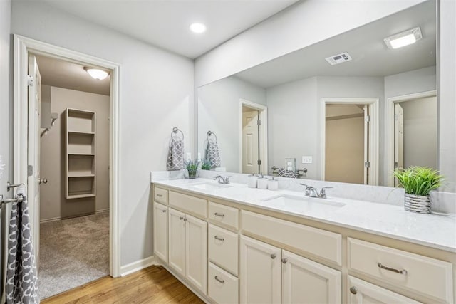 full bath featuring double vanity, wood finished floors, visible vents, and a sink