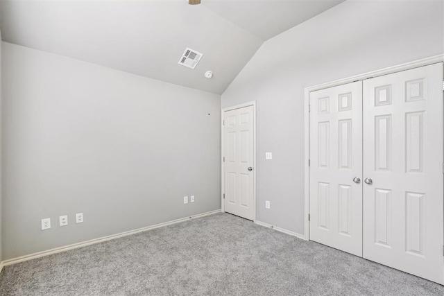 unfurnished bedroom with visible vents, baseboards, lofted ceiling, carpet flooring, and a closet