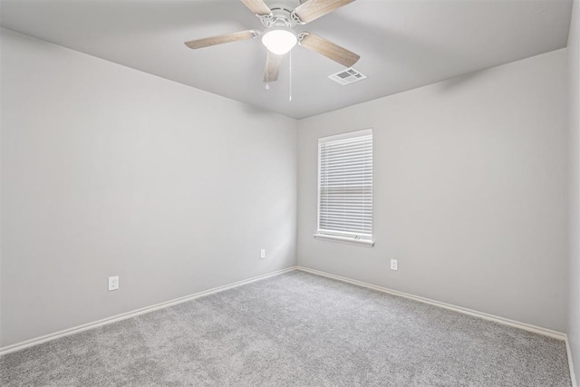 carpeted spare room with visible vents, baseboards, and a ceiling fan