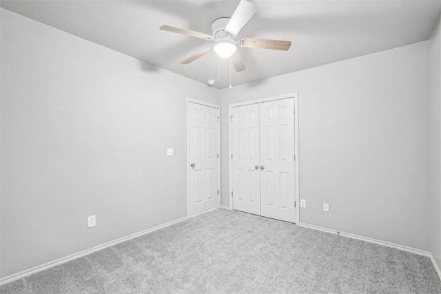 unfurnished bedroom with a closet, carpet flooring, ceiling fan, and baseboards