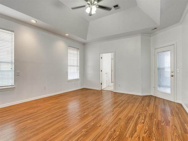 empty room with visible vents, ceiling fan, a tray ceiling, and wood finished floors