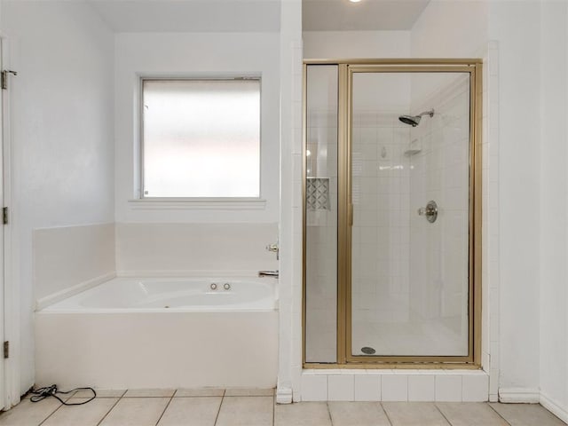 bathroom featuring tile patterned flooring, a bath, and a stall shower