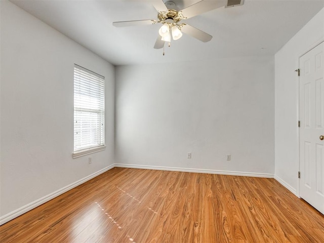 spare room featuring baseboards, light wood finished floors, and ceiling fan