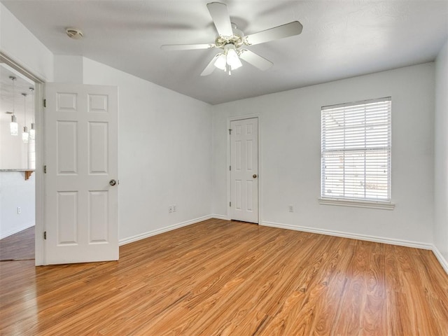 unfurnished room featuring baseboards, light wood-style flooring, and a ceiling fan