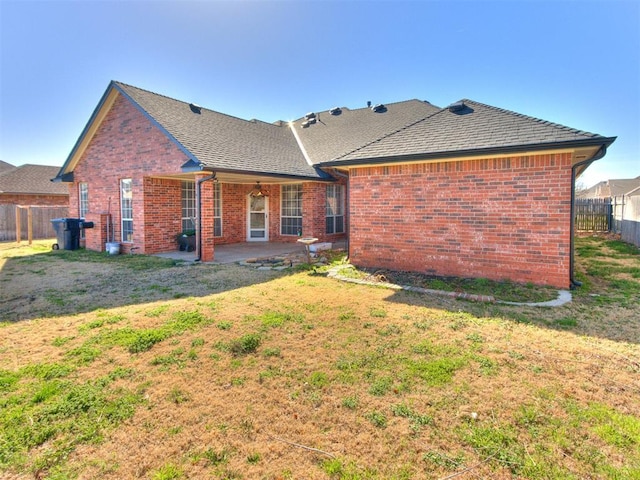 back of property featuring fence, a lawn, brick siding, and a patio area