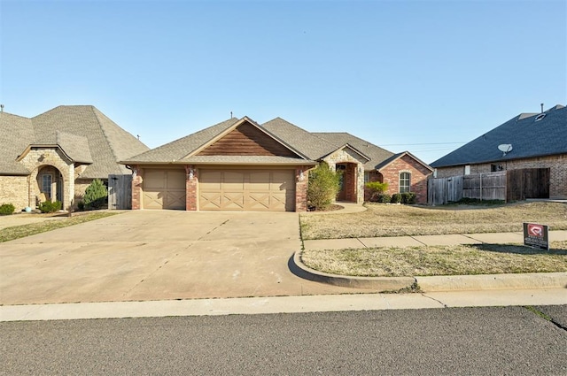 french provincial home with a garage, fence, brick siding, and driveway