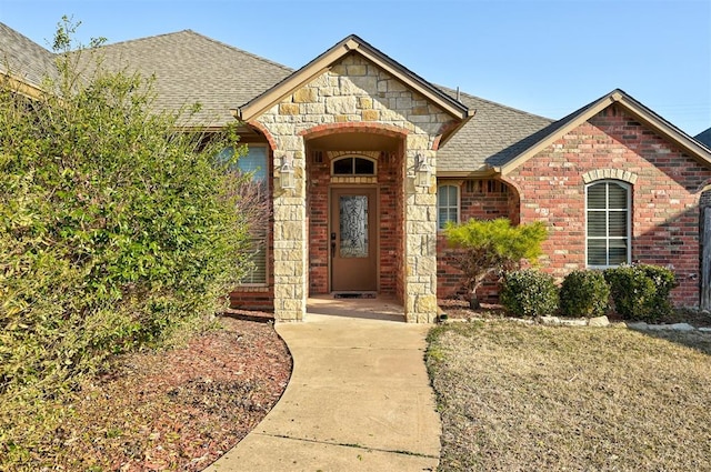 property entrance with brick siding, stone siding, and a shingled roof