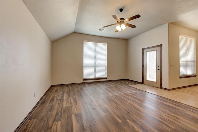 interior space featuring visible vents, wood finished floors, baseboards, ceiling fan, and vaulted ceiling