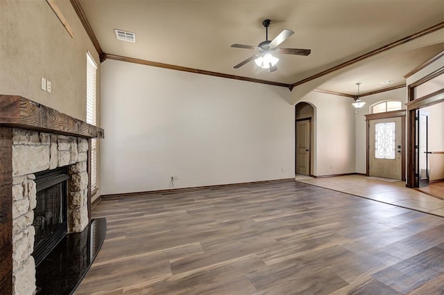 unfurnished living room with arched walkways, visible vents, ceiling fan, and wood finished floors