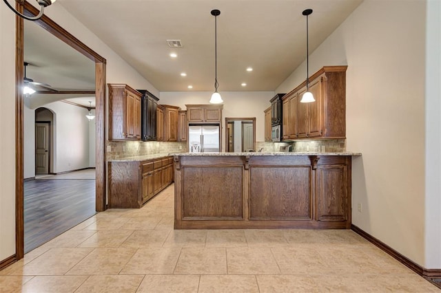 kitchen with stainless steel appliances, arched walkways, tasteful backsplash, and a peninsula