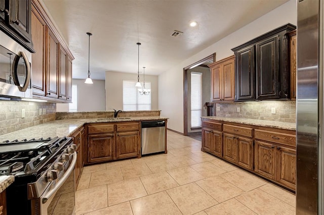 kitchen with light stone countertops, decorative light fixtures, light tile patterned floors, stainless steel appliances, and a sink