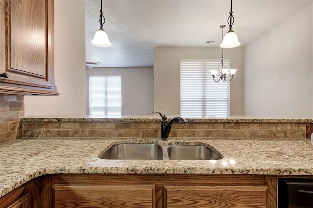 kitchen with dishwasher, light stone counters, visible vents, and a sink