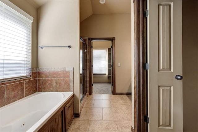 full bathroom featuring a bath, a shower stall, tile patterned floors, and vaulted ceiling