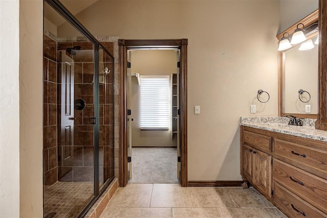 bathroom with baseboards, vanity, a shower stall, and tile patterned flooring