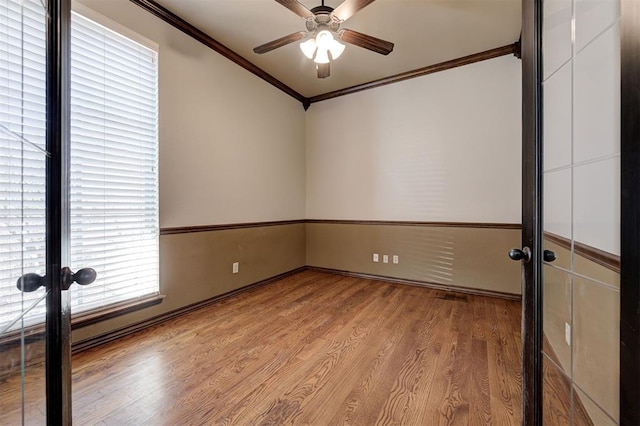 spare room featuring crown molding, wood finished floors, a ceiling fan, and french doors