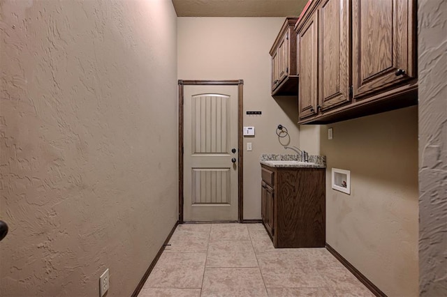 laundry room featuring baseboards, washer hookup, light tile patterned floors, a textured wall, and cabinet space