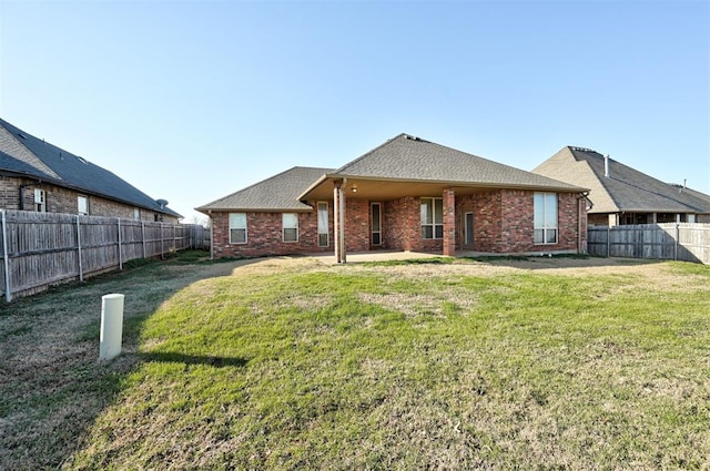 back of property featuring brick siding, a patio area, a fenced backyard, and a lawn