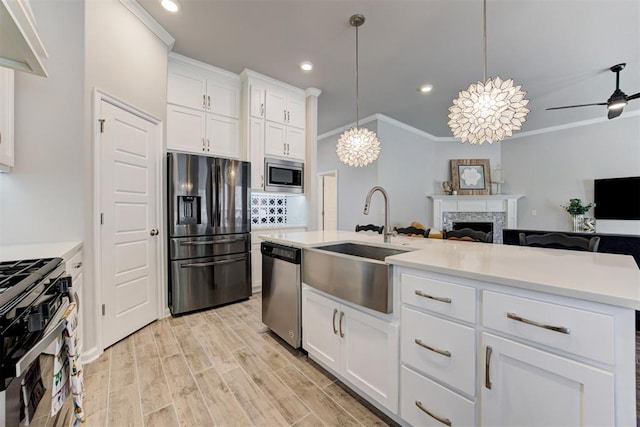 kitchen with recessed lighting, a sink, open floor plan, light countertops, and appliances with stainless steel finishes