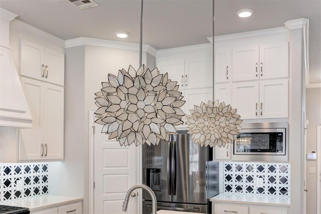 interior details with light countertops, refrigerator with ice dispenser, visible vents, and stainless steel microwave