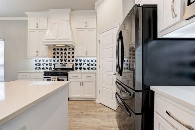 kitchen with premium range hood, freestanding refrigerator, gas stove, and light countertops