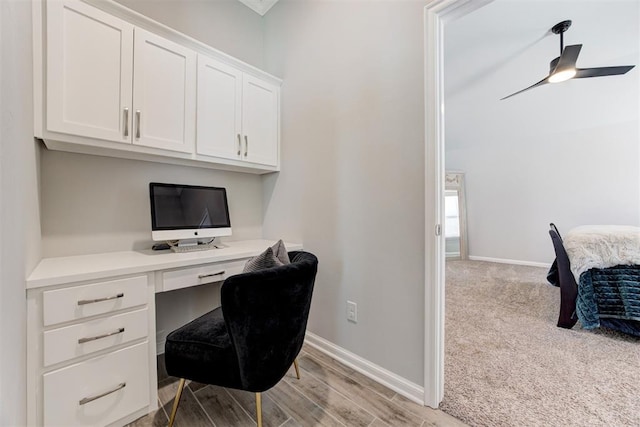 office area with baseboards, light wood-style floors, built in desk, and a ceiling fan
