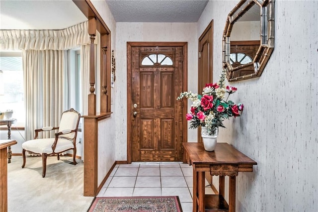 entryway with light tile patterned floors, a textured ceiling, and baseboards