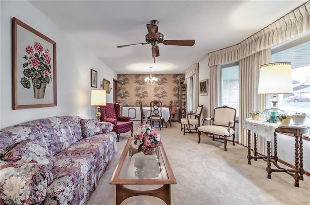 living area with carpet floors, ceiling fan with notable chandelier, and wallpapered walls