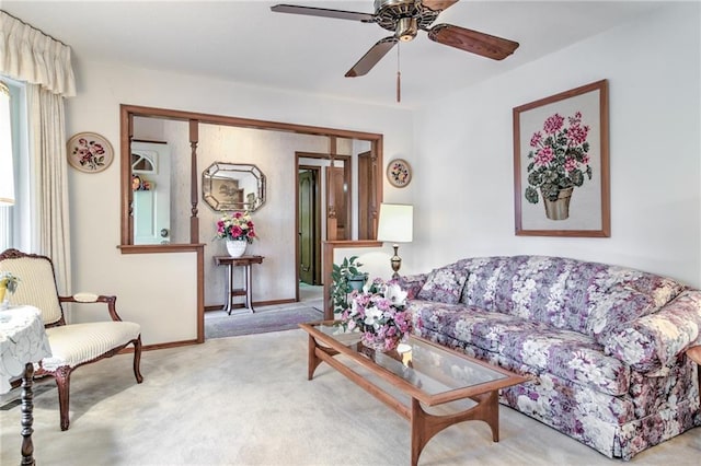 carpeted living room featuring baseboards and ceiling fan