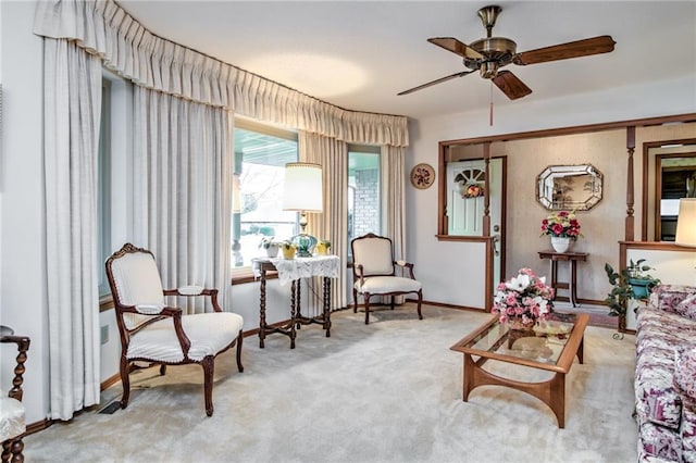 living area featuring baseboards, a ceiling fan, and carpet flooring