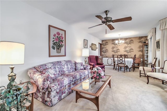 carpeted living area with wallpapered walls and ceiling fan with notable chandelier