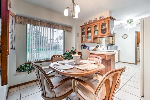 dining area with a textured ceiling, light tile patterned floors, baseboards, and ceiling fan