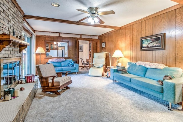 carpeted living room with crown molding, wood walls, a fireplace, a textured ceiling, and a ceiling fan