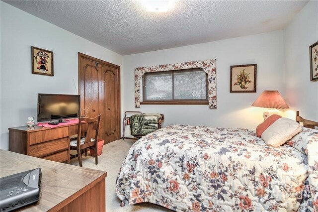 bedroom featuring light carpet, a textured ceiling, and a closet