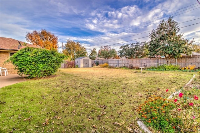 view of yard featuring an outbuilding, a fenced backyard, and a storage shed