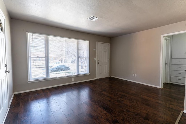 foyer entrance featuring a textured ceiling, dark wood-style floors, visible vents, and baseboards