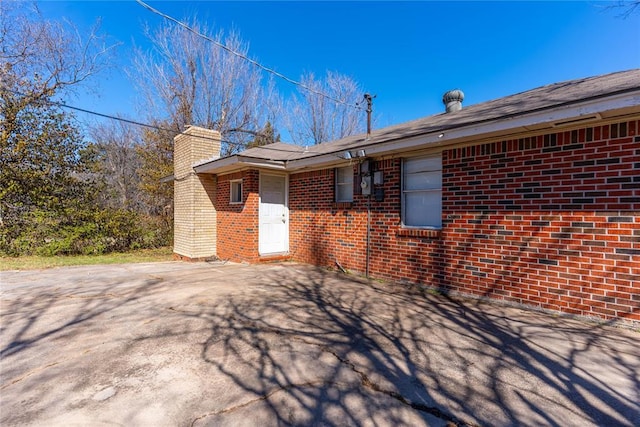 view of side of home featuring brick siding and a chimney