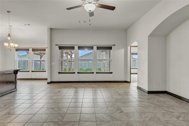 tiled spare room featuring arched walkways, visible vents, ceiling fan with notable chandelier, and baseboards