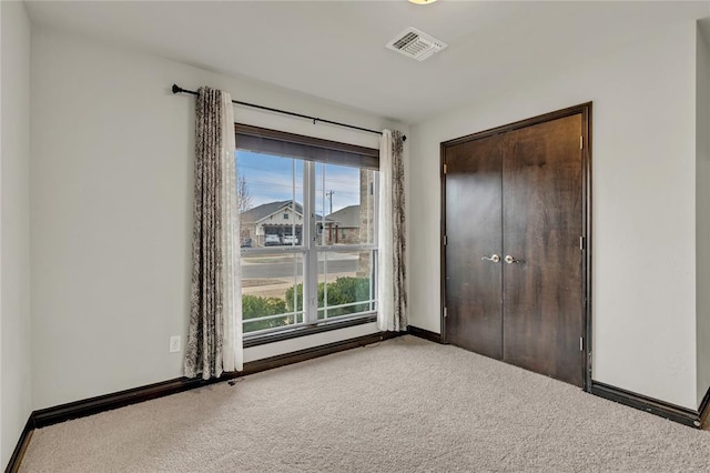 unfurnished bedroom with visible vents, carpet flooring, baseboards, and multiple windows