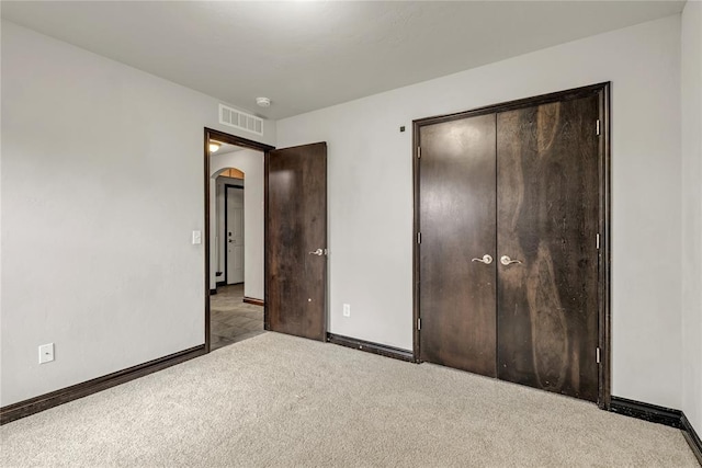 unfurnished bedroom featuring arched walkways, visible vents, baseboards, and carpet floors