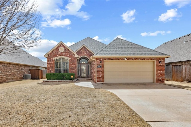 view of front of home featuring central AC, fence, concrete driveway, an attached garage, and brick siding