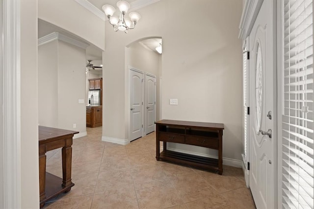 corridor featuring light tile patterned floors, baseboards, arched walkways, and ornamental molding