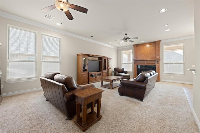 living area with visible vents, ornamental molding, and a ceiling fan