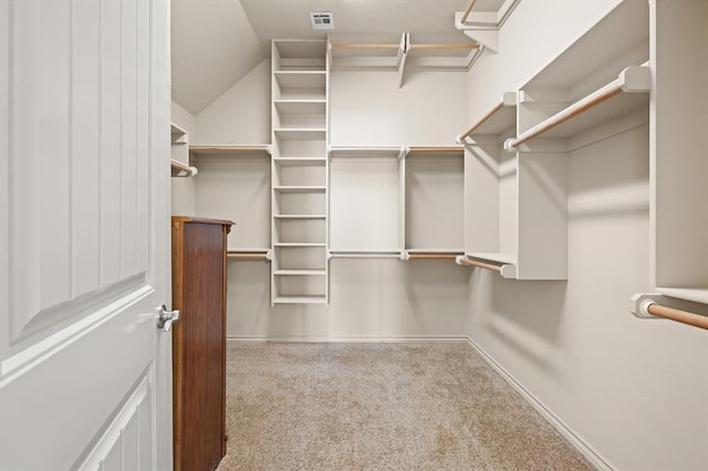 walk in closet with visible vents, lofted ceiling, and carpet floors