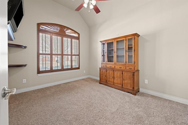 unfurnished room featuring baseboards, lofted ceiling, light carpet, and ceiling fan