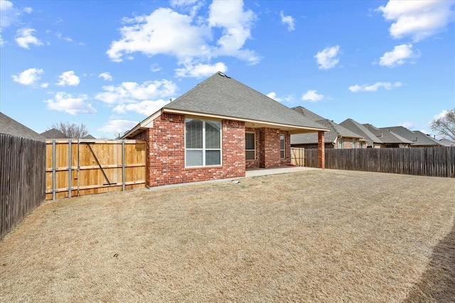 rear view of property with brick siding, a patio, and a fenced backyard