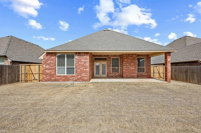 back of property featuring roof with shingles, a fenced backyard, french doors, a patio area, and brick siding