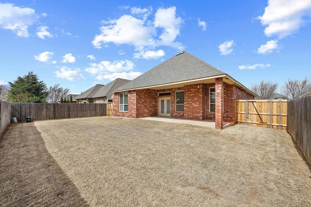 rear view of house featuring a patio, a fenced backyard, and brick siding