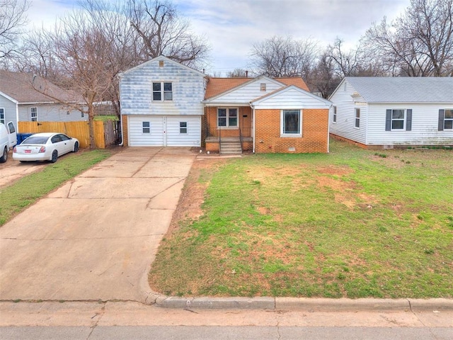 tri-level home featuring brick siding, concrete driveway, a front yard, and fence