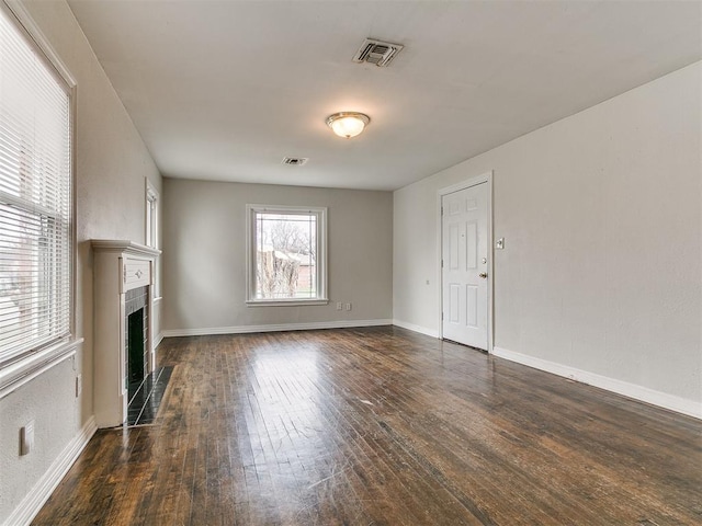 unfurnished living room with visible vents, a fireplace with flush hearth, baseboards, and dark wood-style floors