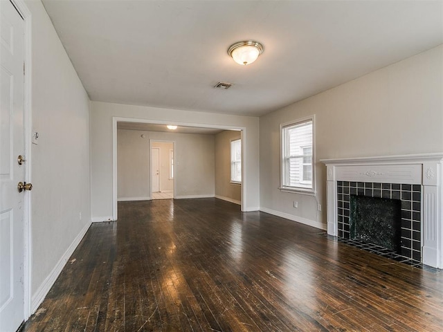 unfurnished living room with visible vents, a tile fireplace, baseboards, and hardwood / wood-style flooring